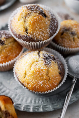 Marmormuffins mit Puderzucker übereinander gestapelt auf einem Teller.