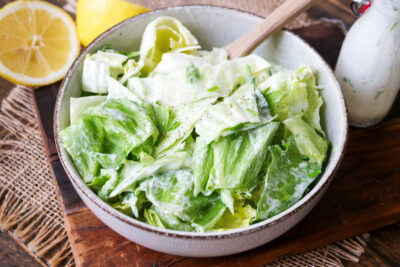 Eisbergsalat in einer Schüssel mit Holzlöffel.