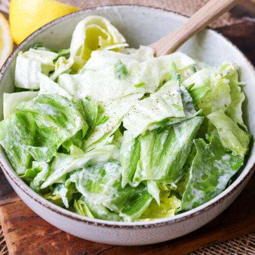 Eisbergsalat in einer Schüssel mit Holzlöffel.