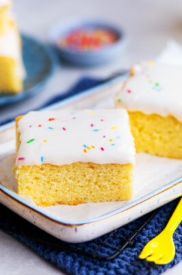 Fantakuchen als Tassenrezept mit Zuckerguss und Streusel auf einem Kuchentablett mit angelegter Gabel.