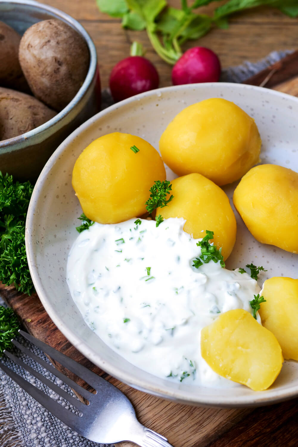 Kartoffeln mit Quark und Petersilie auf einem Teller angerichtet.