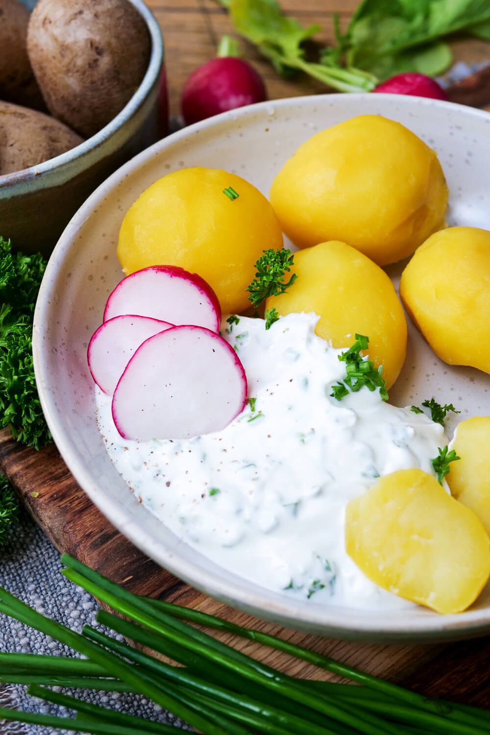 Kartoffeln mit Quark und Radieschen auf einem Teller angerichtet.