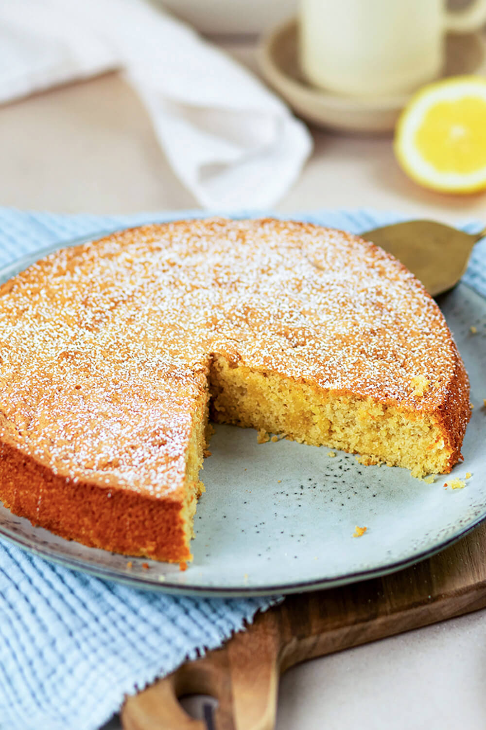 Mallorquinischer Mandelkuchen mit Puderzucker angeschnitten auf einem Teller.