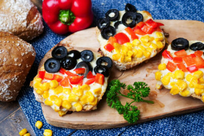 Pizzabrötchen für die Fußball-EM auf einem Holzbrettchen mit Petersilie.