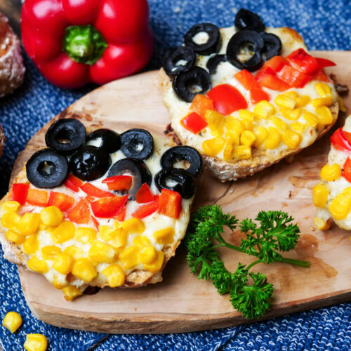 Pizzabrötchen für die Fußball-EM auf einem Holzbrettchen mit Petersilie.