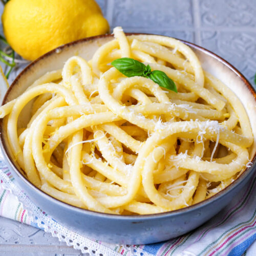 Spaghetti al Limone mit Basilikum auf einem Teller angerichtet.