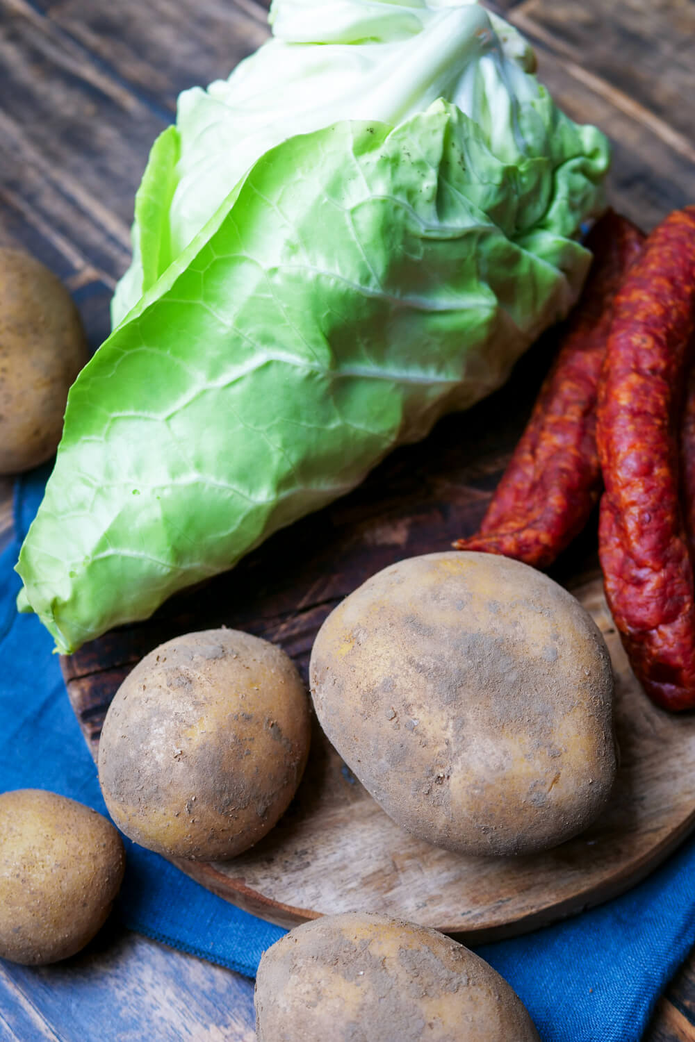 Spitzkohl, Kartoffeln und Metteneden auf einem Holzuntergrund.