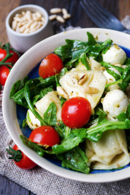 Tortellini-Salat mit Pesto, Tomaten und Rucola in einer Schüssel.