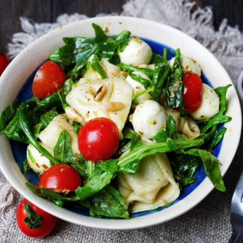 Tortellini-Salat mit Pesto, Tomaten und Rucola in einer Schüssel.