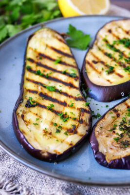 Gegrillte Auberginenscheiben mit Marinade auf einem Teller.