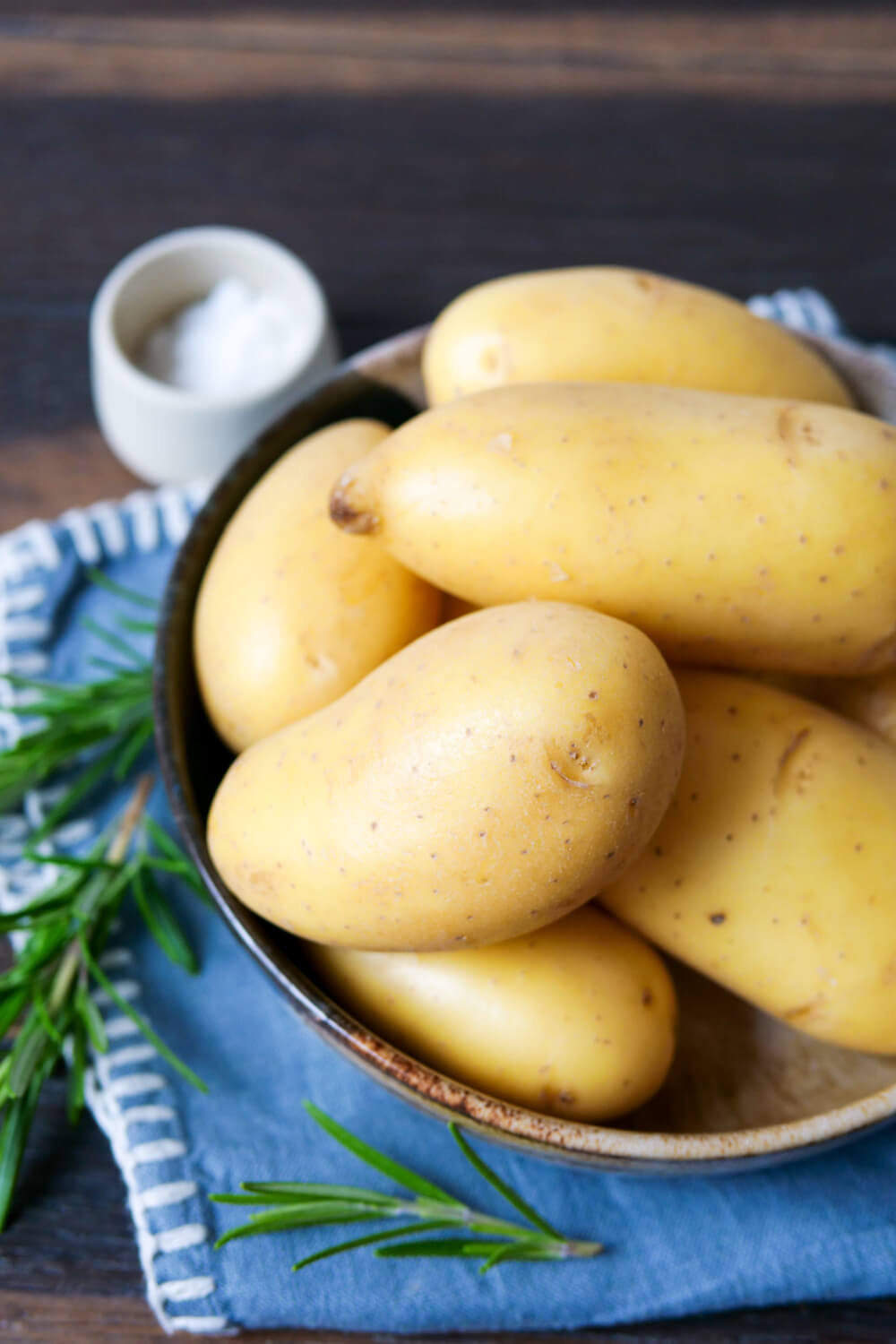 Frühkartoffeln in einer Schale mit Rosmarin daneben.