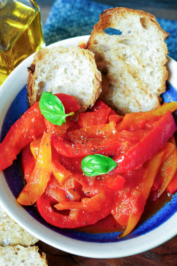 Peperonata Gemüse mit Basilikum und Brot in der blauen Schale