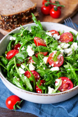 Rucola-Salat mit Feta und Tomaten in einer Schüssel.