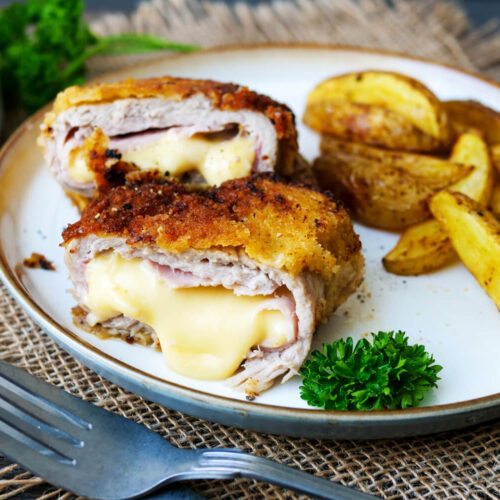 Cordon Bleu angeschnitten mit Kartoffelecken auf einem Teller.