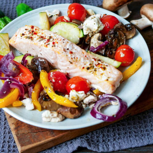 Lachs mit Gemüse im Ofen gegart auf einem Teller angerichtet.