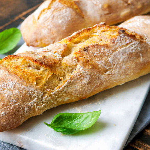 Baguette auf einem Marmorbrettchen mit Basilikum.