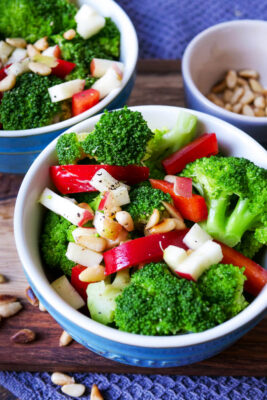 Brokkoli-Salat mit Paprika, Pinienkernen und Apfel in einer Schale.