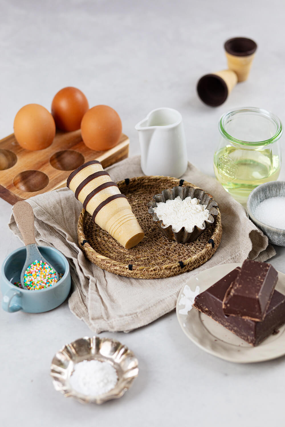 Die Zutaten für Kuchen im Waffelbecher auf hellem Untergrund.