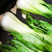 Pak Choi mit Knoblauch in einer Pfanne.