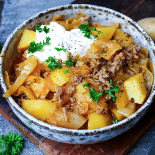 Schichtkohl mit Hackfleisch, Kartoffeln und Schmand in einer Schale.