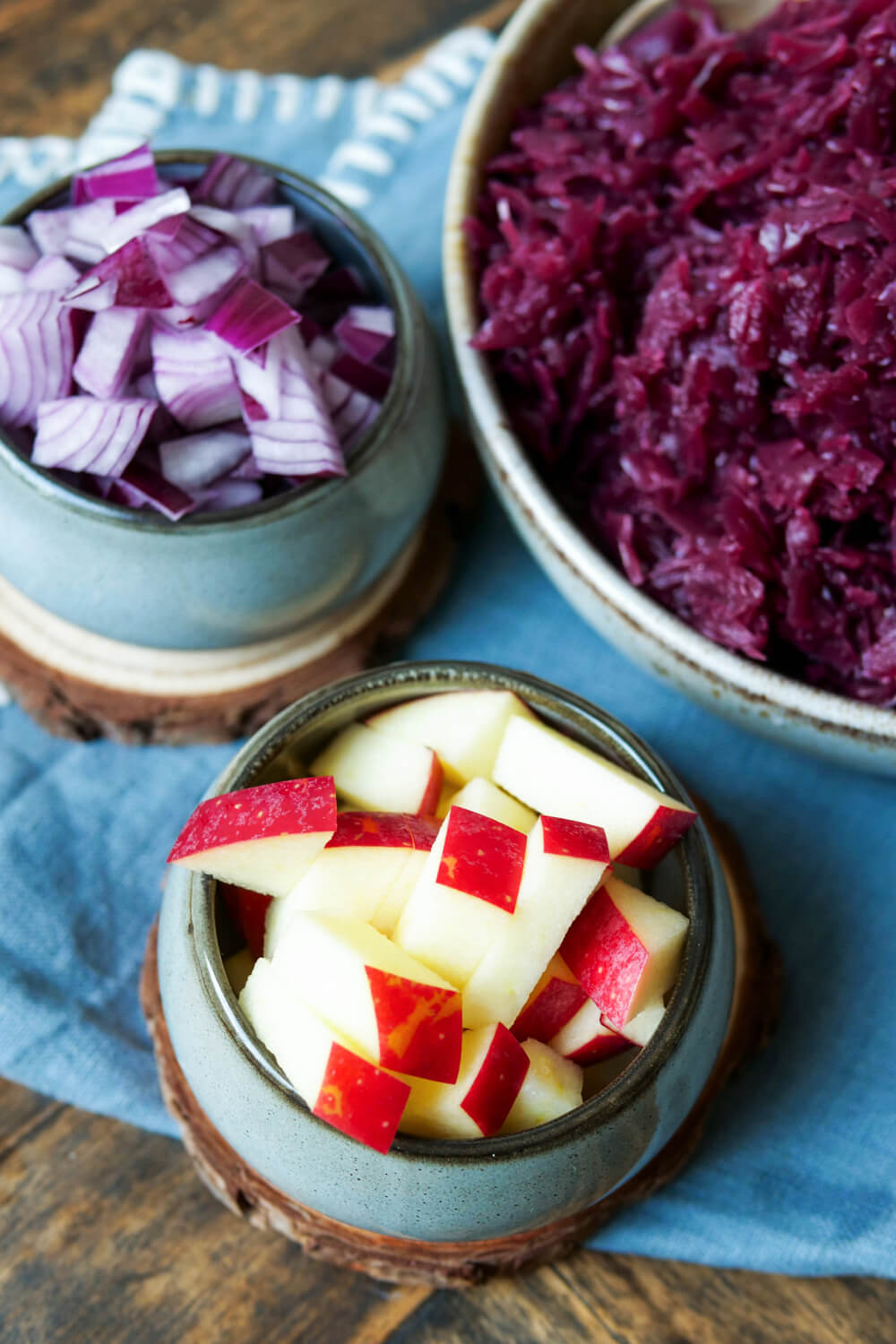 Geschnittener Apfel und Zwiebel neben Rotkohl in einer Schale.