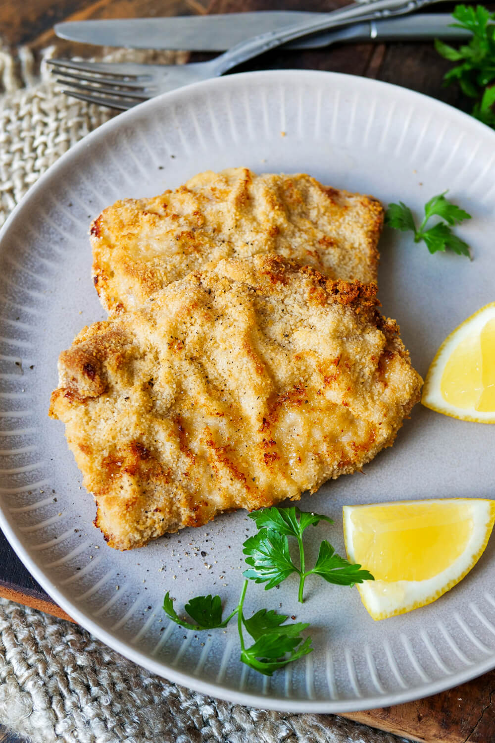 Panierte Schnitzel aus der Heißluftfritteuse auf einem Teller mit Zitrone und Petersilie.