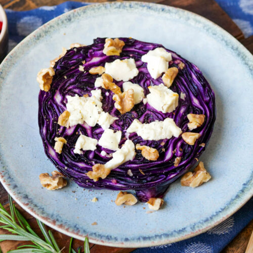 Rotkohl-Steak mit Feta und Walnüssen auf einem Teller.