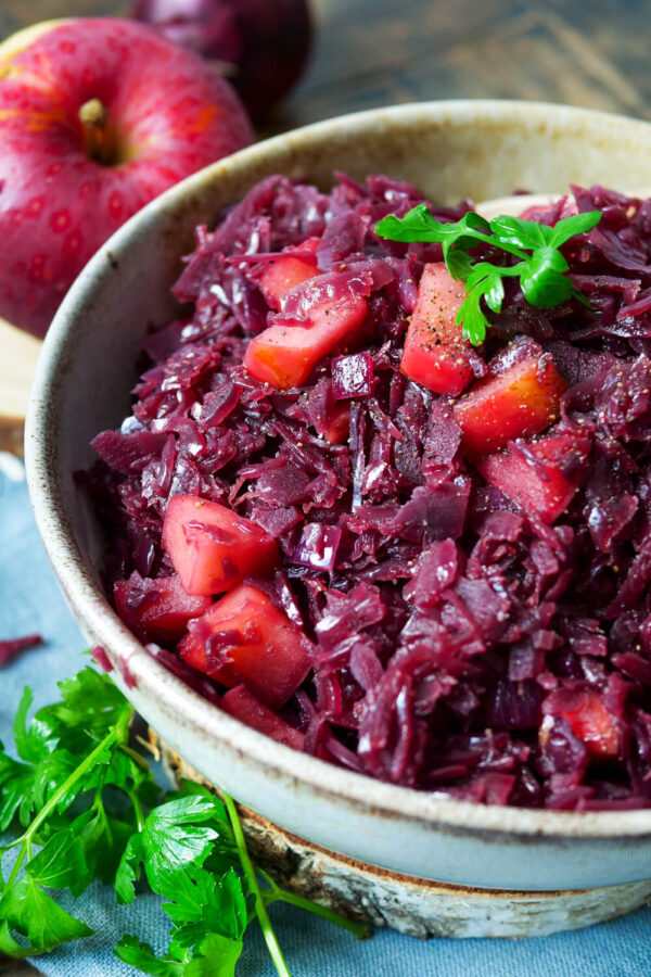 Verfeinerter Rotkohl aus dem Glas mit Apfel in einer Schale.