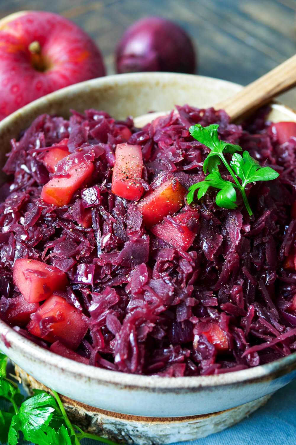 Verfeinerter Rotkohl mit Apfel aus dem Glas in einer Schale mit Holzlöffel.