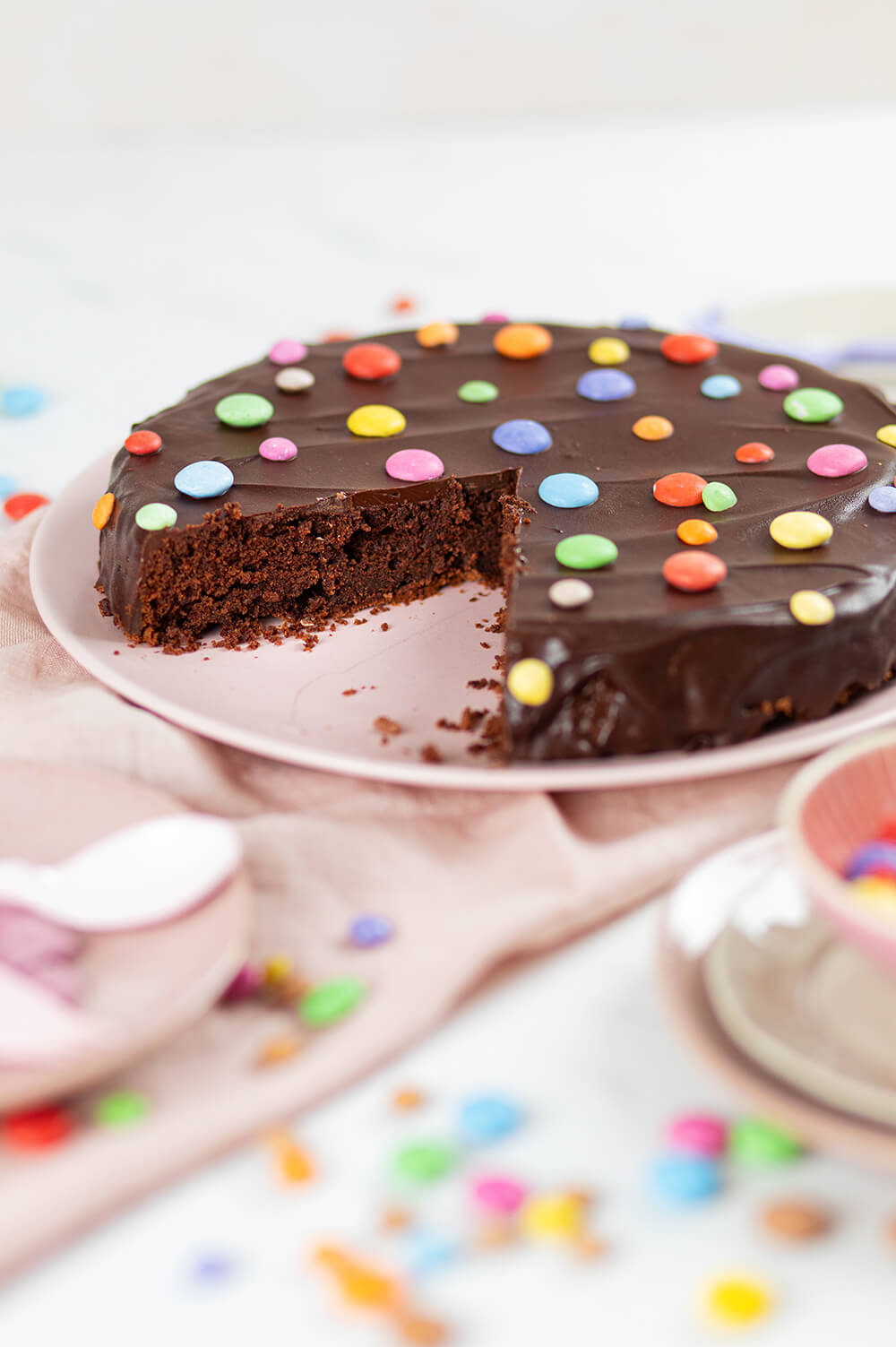 Smarties-Kuchen angeschnitten auf einer Kuchenplatte.