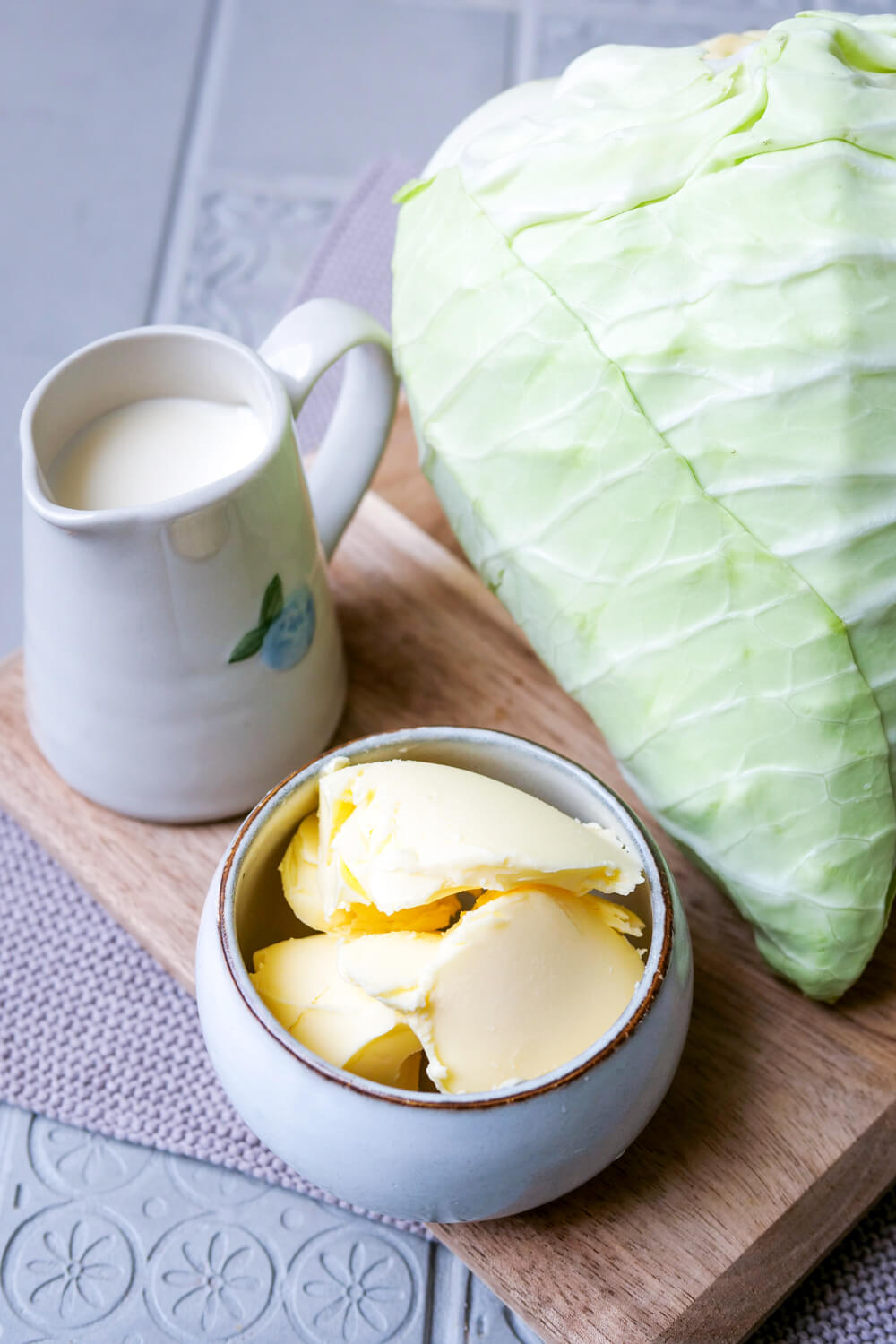 Butter, Sahne und Spitzkohl auf einem Holzbrett.